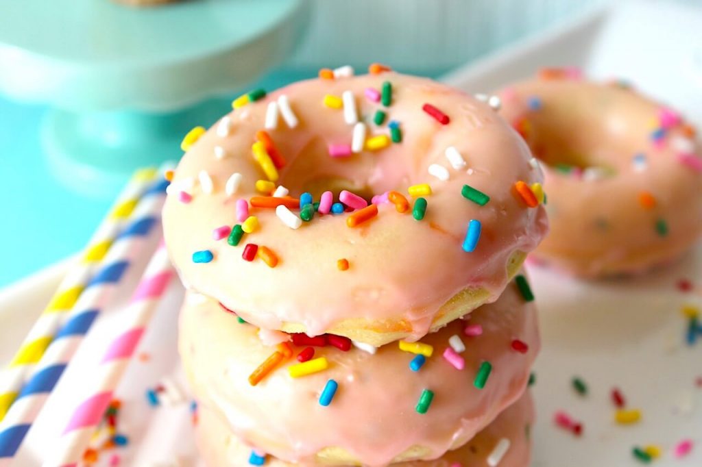 stack of 3 pink donuts with sprinkles