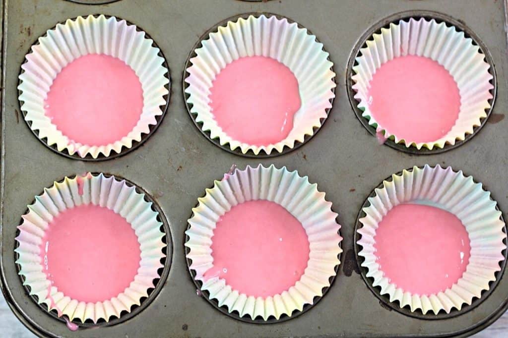 pink cake batter in cupcake tin. 