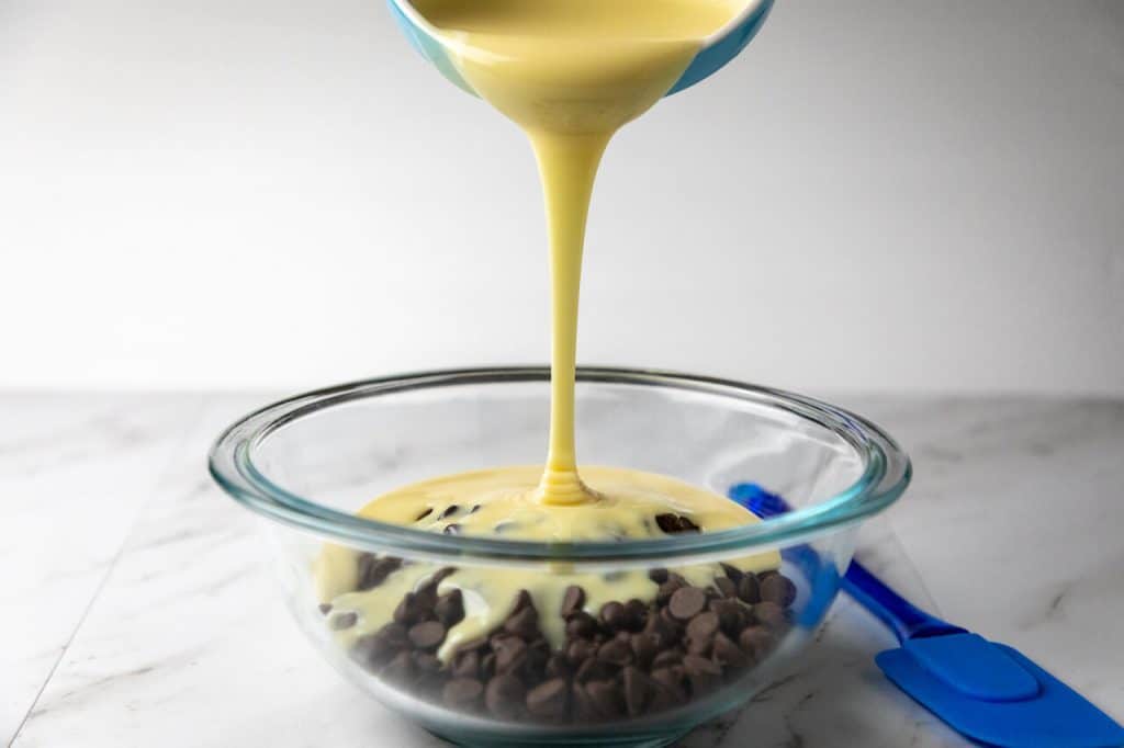 condensed milk being poured into chocolate chips