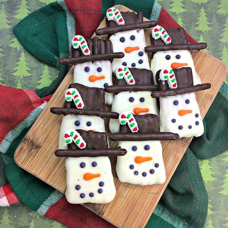 chocolate covered snowman pretzels on a board
