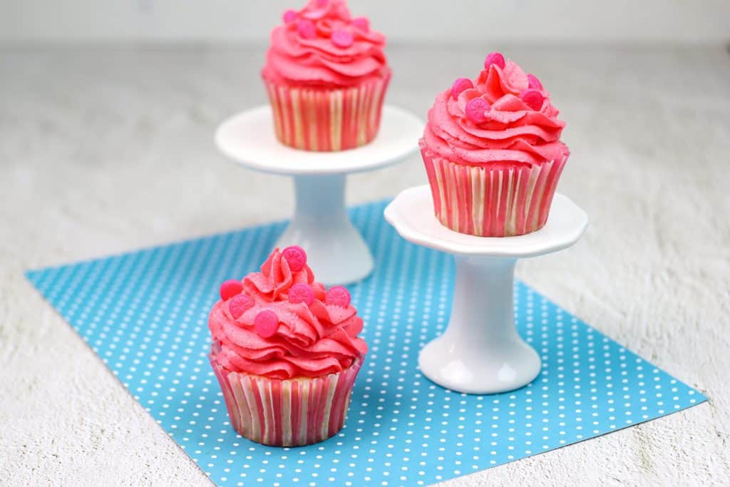 pink cupcakes with pink frosting on tiered stands.