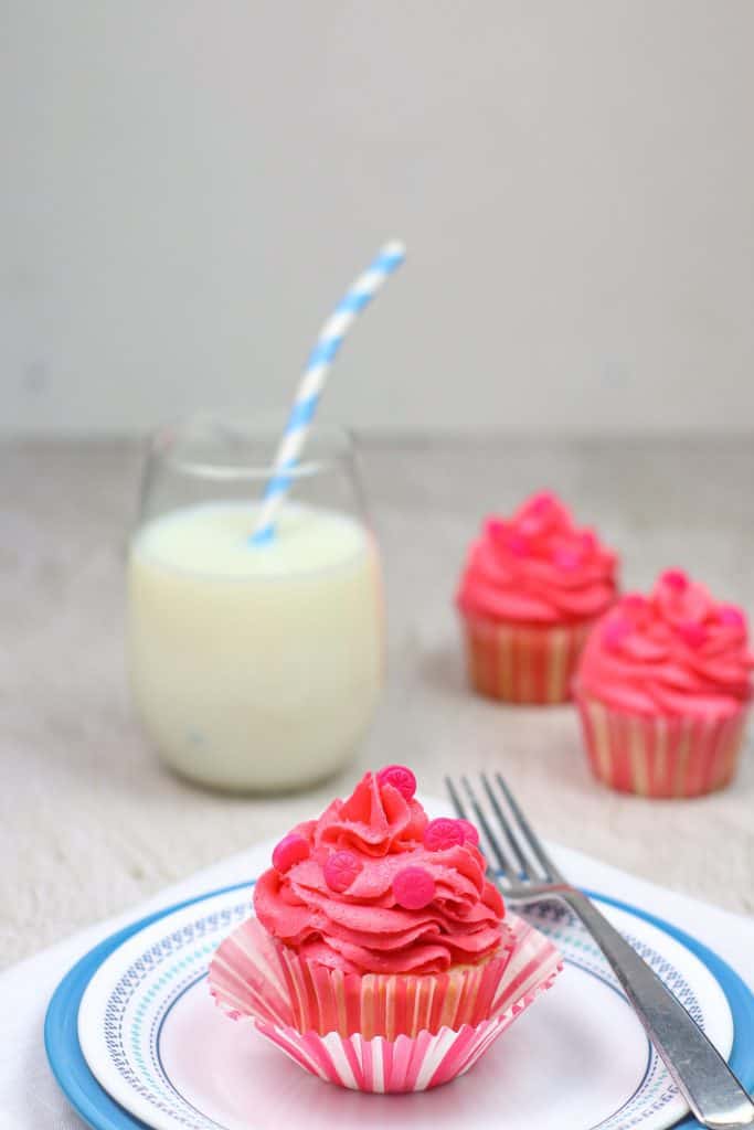 grapefruit cupcake on a plate with a fork and milk with a straw.