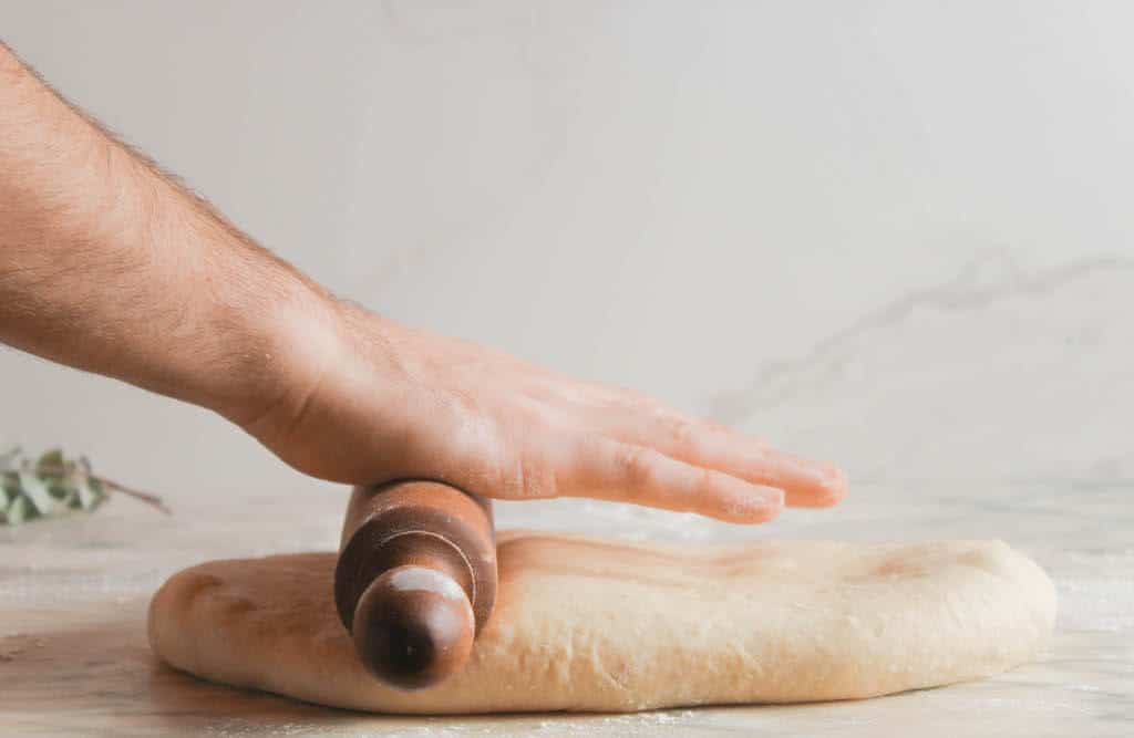 rolling the donut dough with a rolling pin.