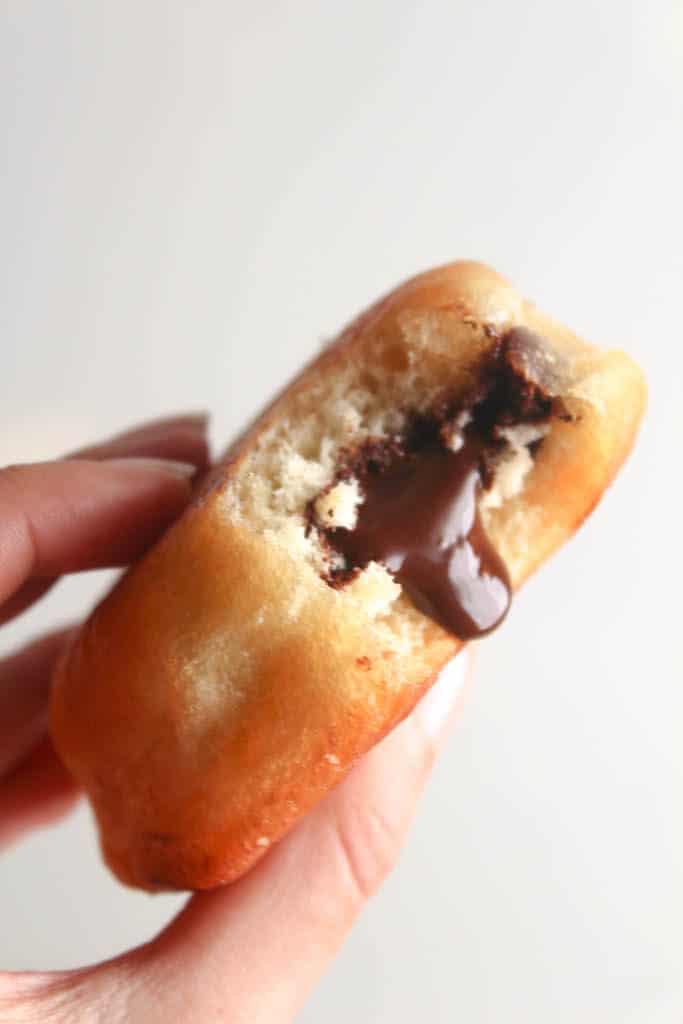 homemade donut with bite taken out and chocolate filling oozing out.