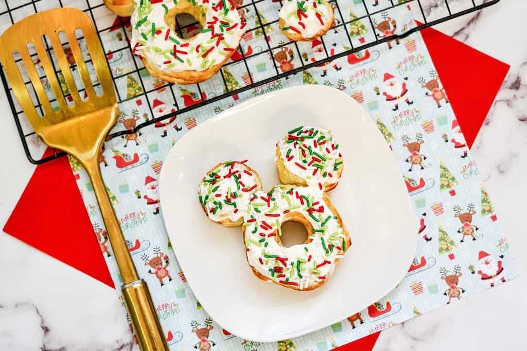 Mickey Mouse donuts with frosting and sprinkles on a plate. 