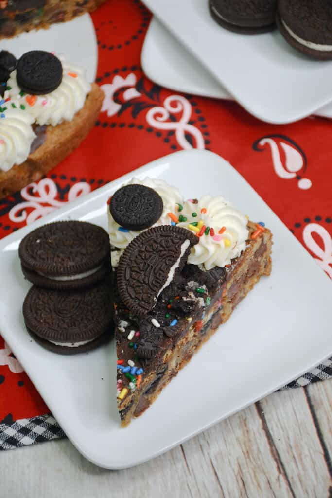 slice of Oreo chocolate chip cookie cake on a plate with oreos. 