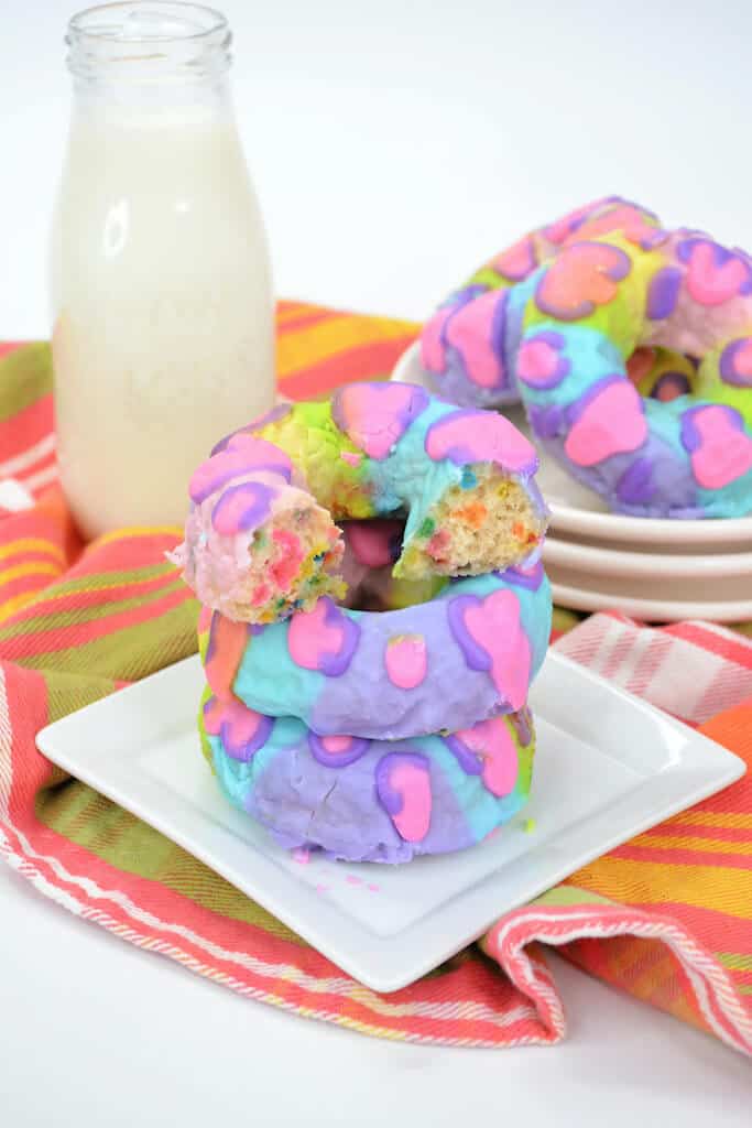 stack of 3 colorful donuts on a plate. 