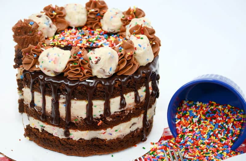 A brownie chocolate chip cake beside a colored rainbow sprinkles.