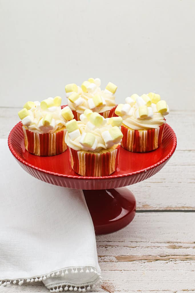 4 Buttered Popcorn Cupcakes on a red platter.