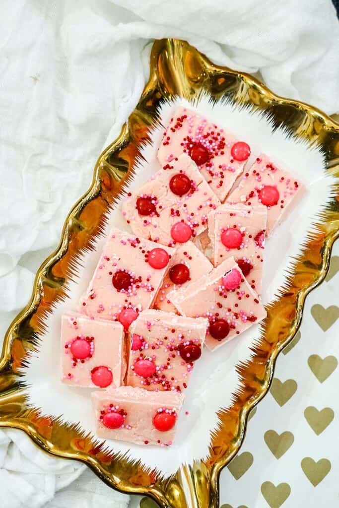 Strawberry Fudge cut into pieces on a white and gold tray.