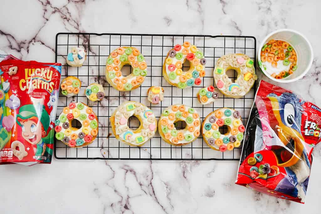 Frosted air fryer cereal donuts on cooling rack.