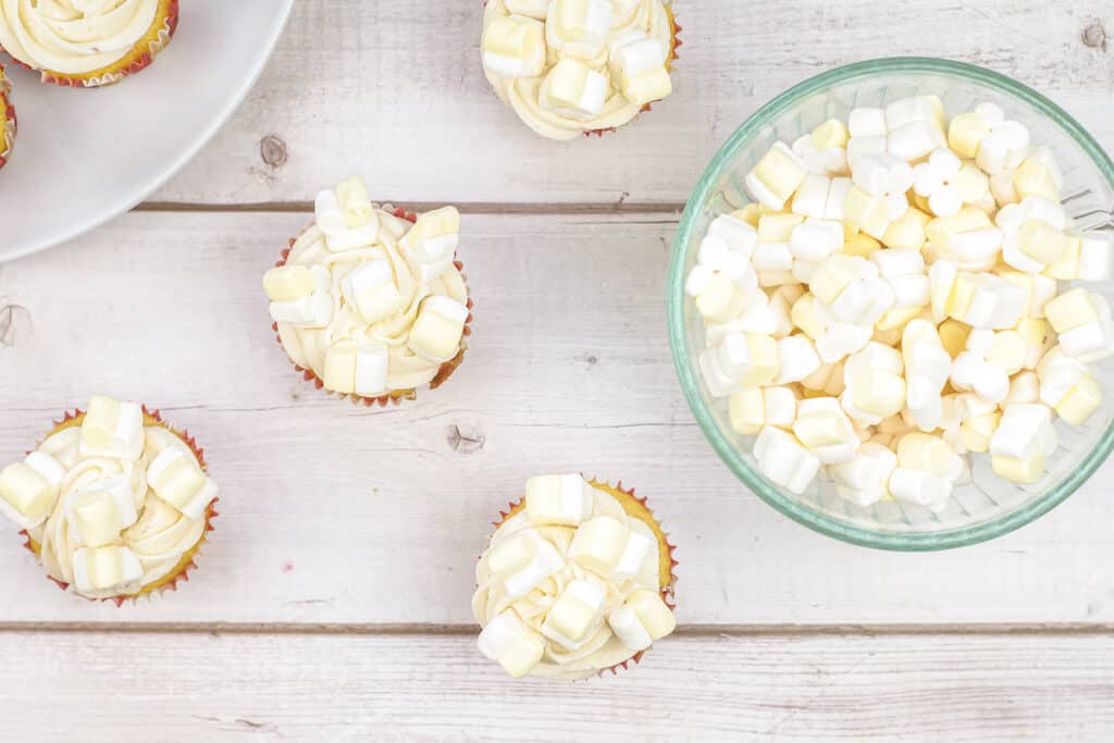 Marshmallow in a Glass bowl beside of popcorn butter cupcakes.
