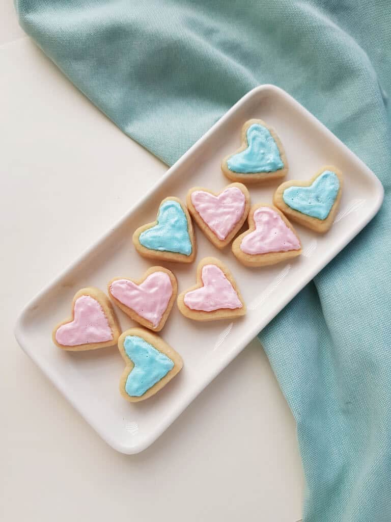 Heart sugar cookies with frosting on a tray.